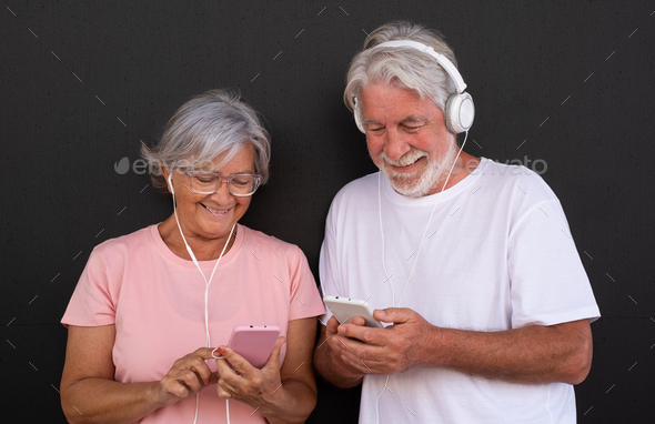 Portrait of attractive senior couple using mobile phones. Elderly retiree enjoying social and tech - Stock Photo - Images