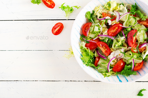 Fresh tomatoes with cucumber, lettuce, red onion and spices in a white bowl - Stock Photo - Images