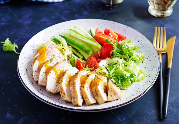 Fried chicken fillet and fresh vegetable salad of tomatoes, cucumbers and lettuce - Stock Photo - Images