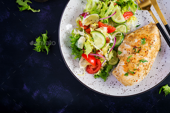 Fried chicken fillet and fresh vegetable salad of tomatoes, cucumbers and lettuce - Stock Photo - Images