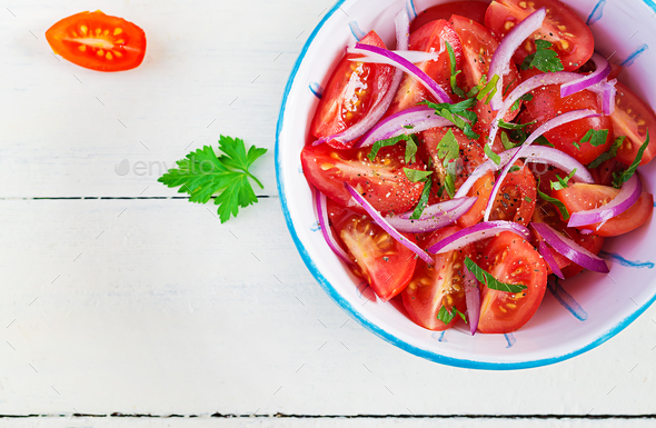 Fresh tomatoes with red onion and spices in a blue bowl - Stock Photo - Images