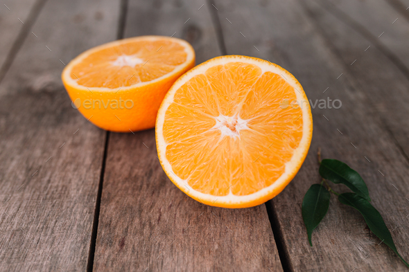 Halves of orange fruit on gray wooden background. Orange pulp and green leaves - Stock Photo - Images