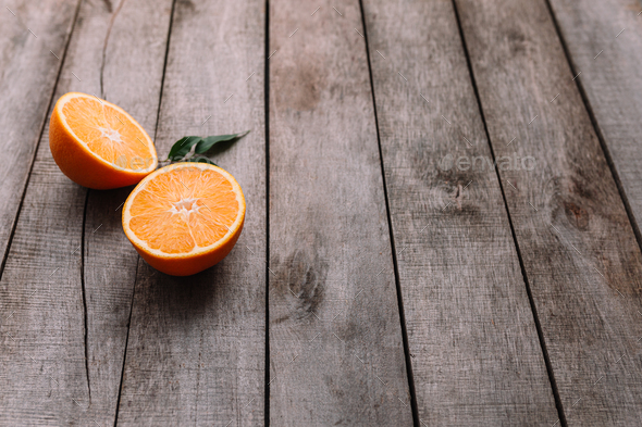Halves of orange fruit on gray wooden background. Orange pulp and green leaves - Stock Photo - Images