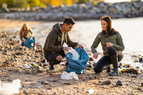 Team of hard working volunteers collecting plastic garbage at beach - Stock Photo - Images