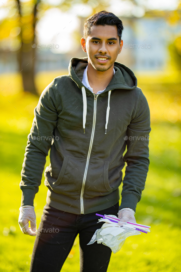Back lit portrait of man cleaning garbage on sand at park - Stock Photo - Images
