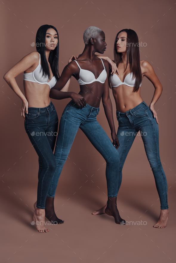 So hot! Full length of three attractive young women posing while standing against brown background