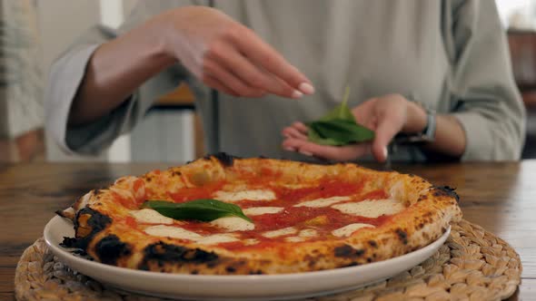Chef in the Pizzeria Prepares a Pizza and Decorates It with Parmesan Cheese Pepper and Basil alt