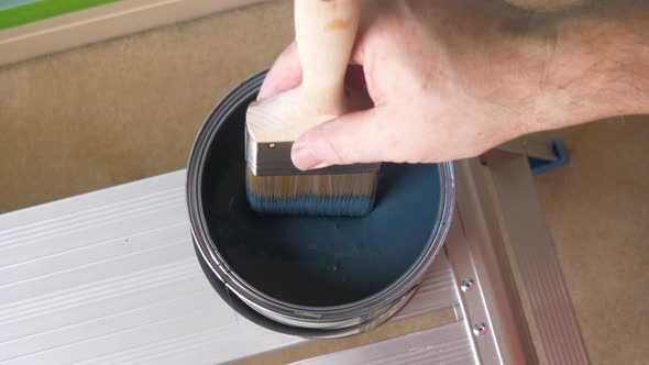 Home decorating, painter dipping paintbrush in modern blue paint pot