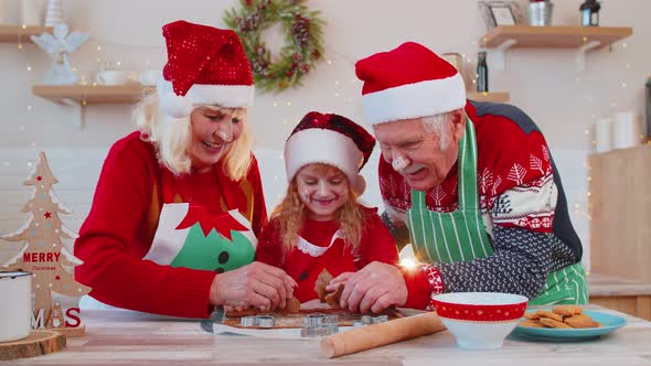 Senior Family Grandparents with Granddaughter in Santa Claus Hats Preparing Cooking Homemade Cookie alt