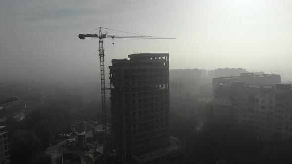 Birds eye view on tower crane in fog standing next to residential building.  alt