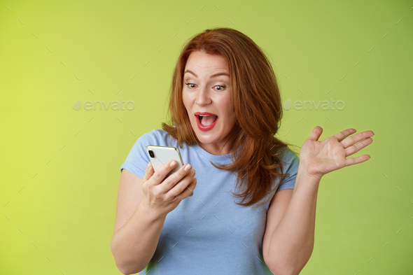 Surprised Glad Middle Aged Pretty Redhead Woman Look Smartphone Raise