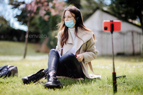 young woman student virtual learning on mobile wearing medical mask new normal