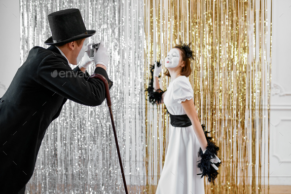 Mime artists, lady poses at gentleman with camera