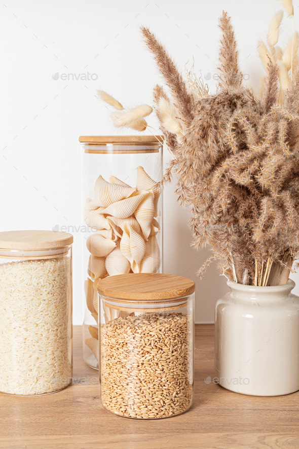 Assortment of grains, cereals and pasta in glass jars on wooden