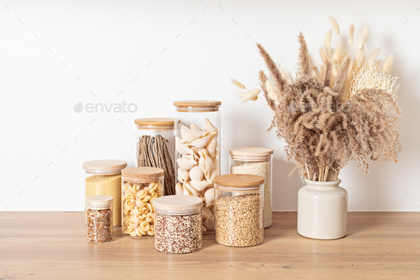 Assortment of grains, cereals and pasta in glass jars on wooden