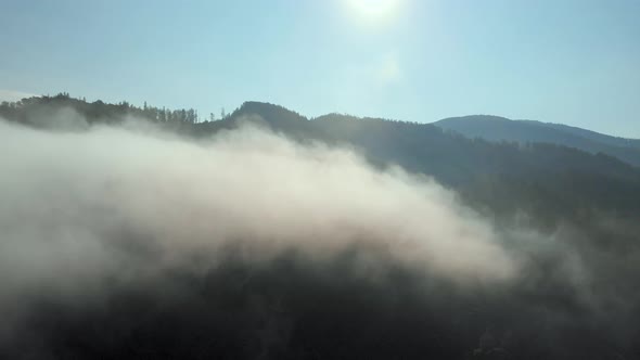 Aerial drone shot of amazing dense fog above river between mountains.
