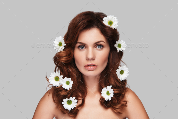 Time for yourself. Attractive young woman looking at camera while standing against grey background