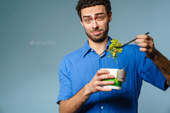 Confused handsome guy eating salad takeaway on camera