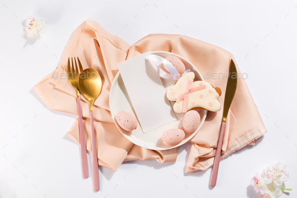 Easter table place setting with eggs, bunny cookies, plate, cutlery and beautiful flowers with menu