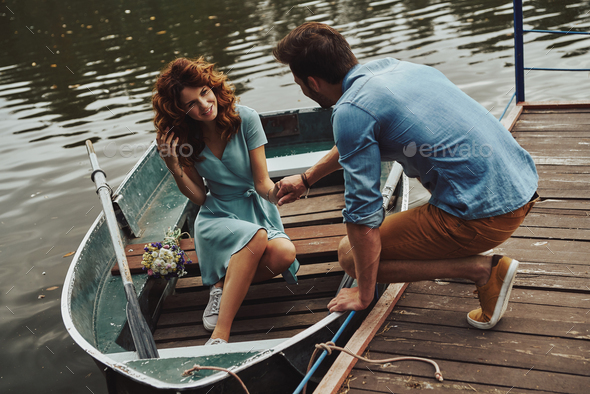 Romantic date. Happy young couple getting ready to row a boat while enjoying their date outdoors