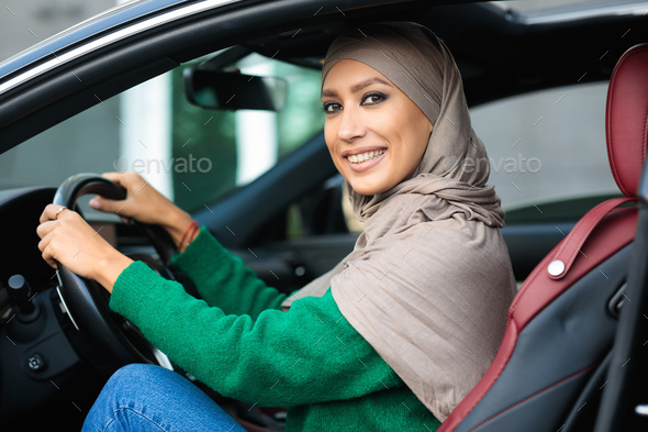 Cheerful smiling muslim woman test driving her new car