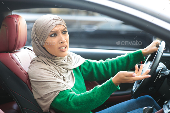 Angry muslim woman in hijab driving her car and arguing