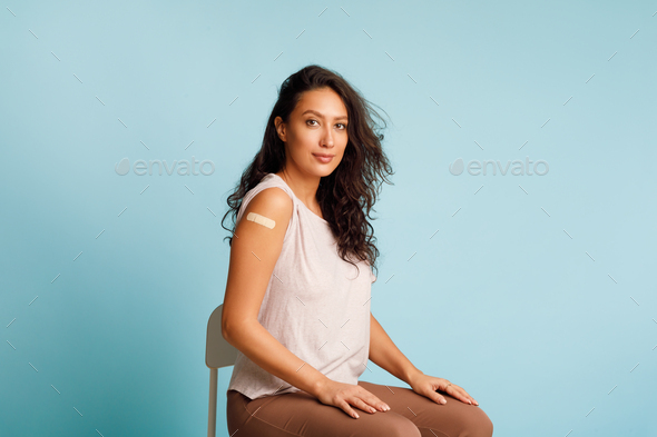 Vaccinated Woman Showing Arm Sitting With Rolled Up Sleeves, Studio