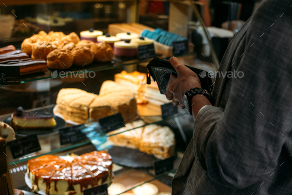 Confectionery customer, client in sweet-shop, pastry-shop. Back view of young woman choosing cake