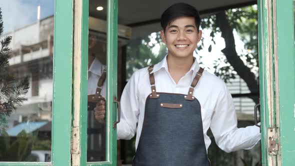 Young man open the door of his coffee cafe shop.