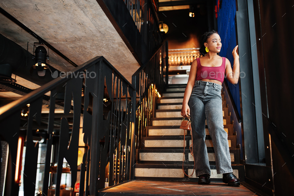 African woman in red marsala top and jeans posed indoor. Stock Photo by ...