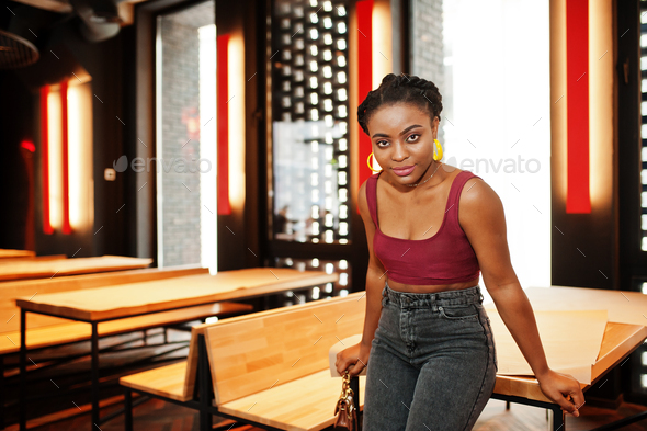 African woman in red marsala top and jeans posed indoor. Stock Photo by ...