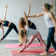 Three teenage girls doing yoga in the gym with the instructor. A