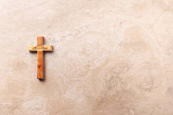 Wooden cross with text He is risen on marble background. Reminder of Jesus sacrifice and Christ