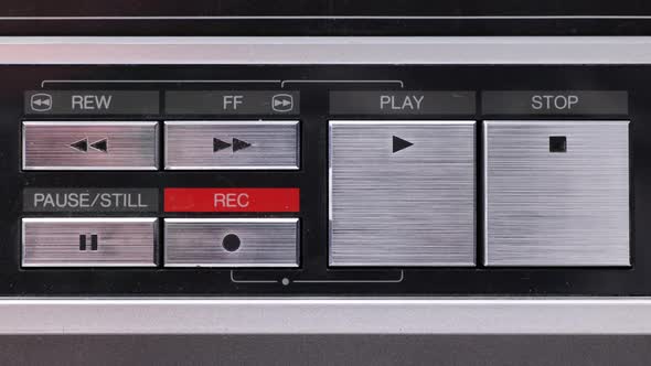 Extreme close up of buttons on an old antique or vintage VCR a finger coming in and pushing Play. alt