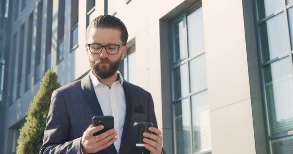 businessman in formal suit has phone call during coffee time near big city building alt