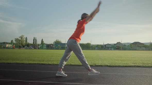 Young Beautiful Girl in Sweatpants and an Orange Tshirt Goes in for Sports alt