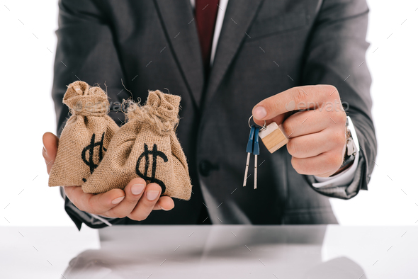 cropped view of mortgage broker holding keys and moneybags isolated on white