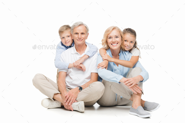 smiling children hugging grandparents and looking at camera isolated on white
