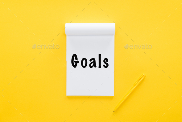top view of notebook with \'goals\' word on yellow, goal setting concept