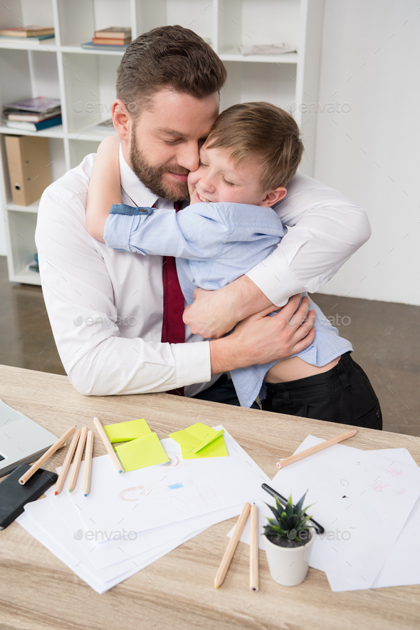 Businessman hugging with son at office