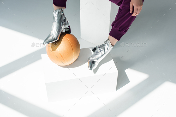 cropped shot of woman in silver colored boots with basketball ball