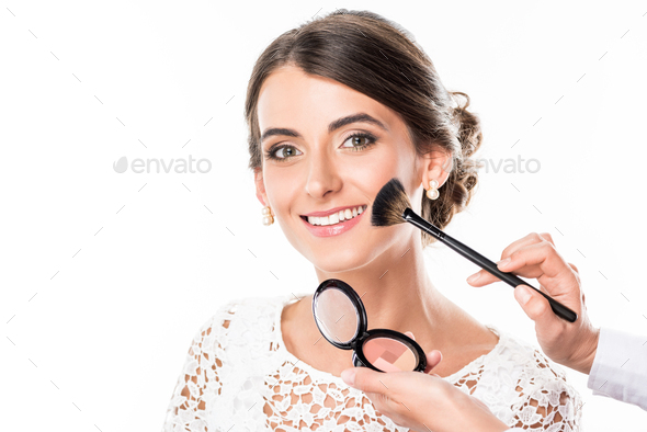 partial view of makeup artist applying blush on models face isolated on white
