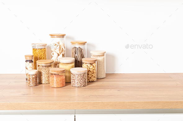 Assortment of grains, cereals and pasta in glass jars on wooden