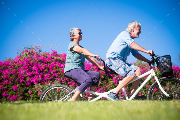 beautiful and cute couple of mature and old woman and man riding together a double bike