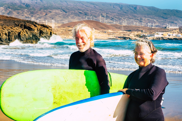 Couple Of Mature And Old People Or Seniors Surfing Together In The Beach With A Big Surfboard 7738