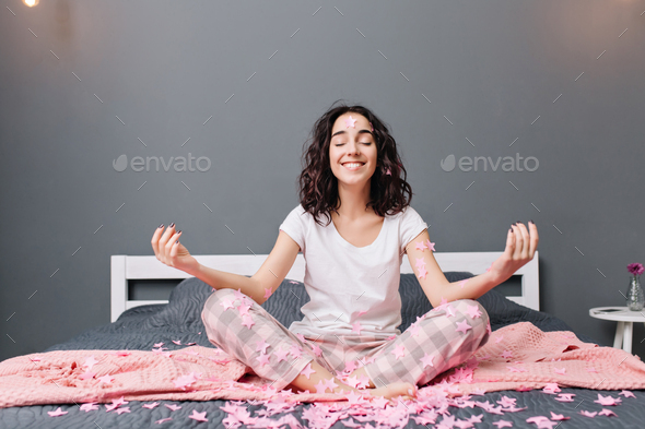 Joyful beautiful young woman in pajamas with curly brunette hair