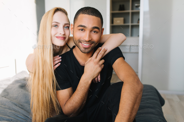 Joyful pretty young woman with long blonde hair hugging handsome guy from back. Couple in love chill