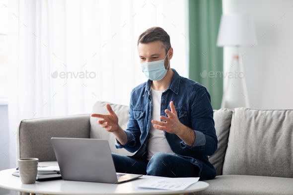 Businessman in face mask having video business conference from home