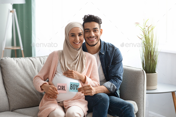 Gender Reveal Concept. Young islamic spouses holding boy and girl sticker cards