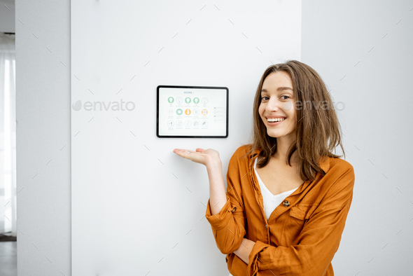 Portrait of a happy woman controlling home with a digital tablet